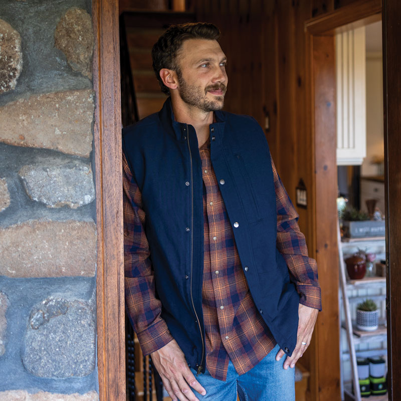 Man standing in doorway of wood cabin during Fall.