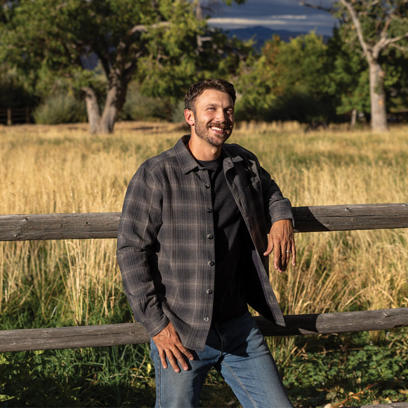 Man leaning on wooden fence in field during Fall.
