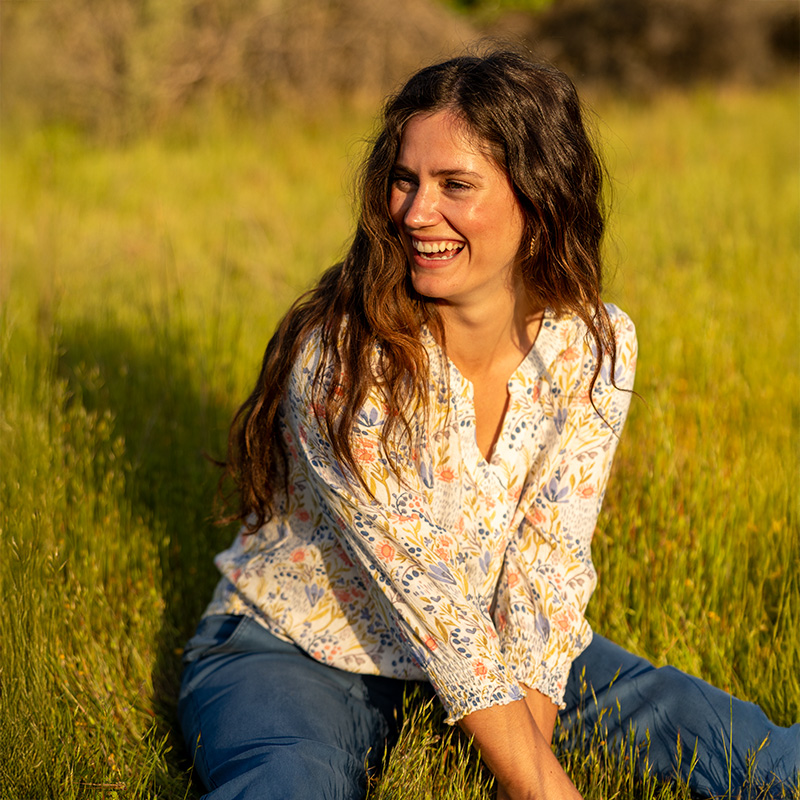 Woman sitting in field during spring sunset.